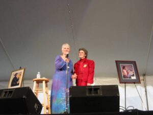 Connie Regan-Blake welcoming Rosa Hicks on stage at the National Storytelling Festival in 2003. The tent was filled with Ray's devoted fans, listeners and storytellers who gathered to remember him in story and song. (Photo by: Tom Raymond)